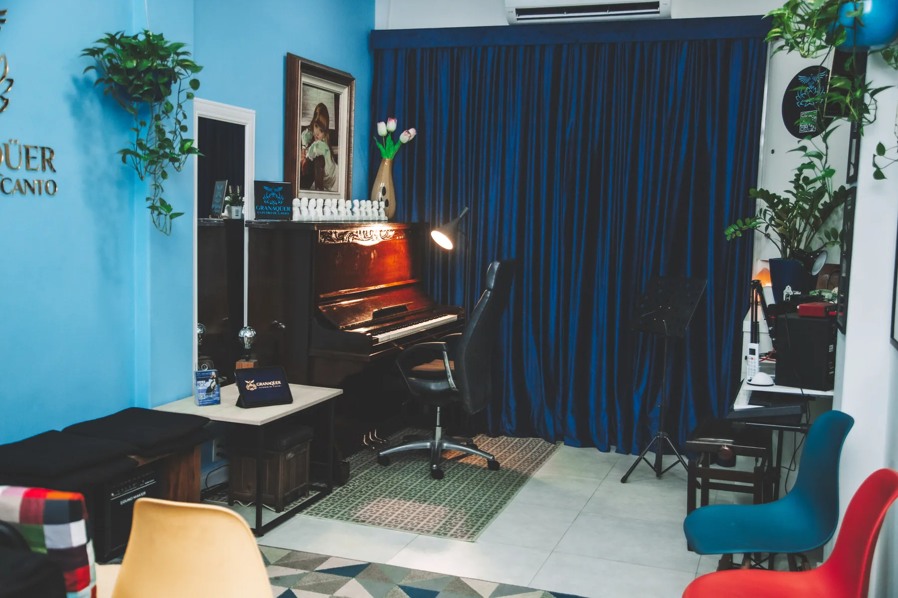 Piano acústico do Granaqüer diante da cortina azul, com estante de partitura e bustos de compositores
